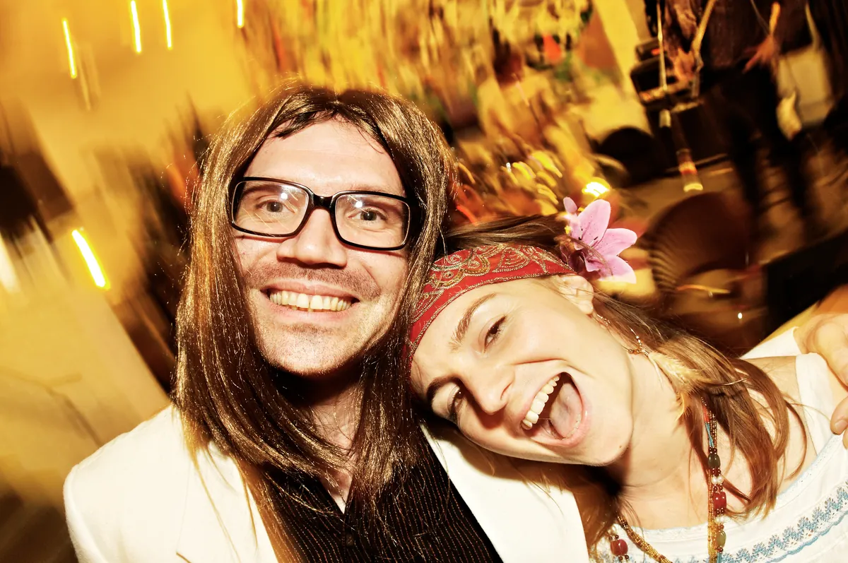 Two party guests in costume laughing into the camera