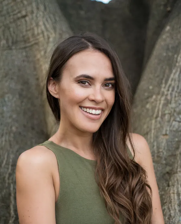 Portrait of a smiling woman with long hair in front of a tree