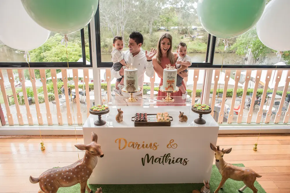 Family celebrating behind a decorated cake table at a birthday party