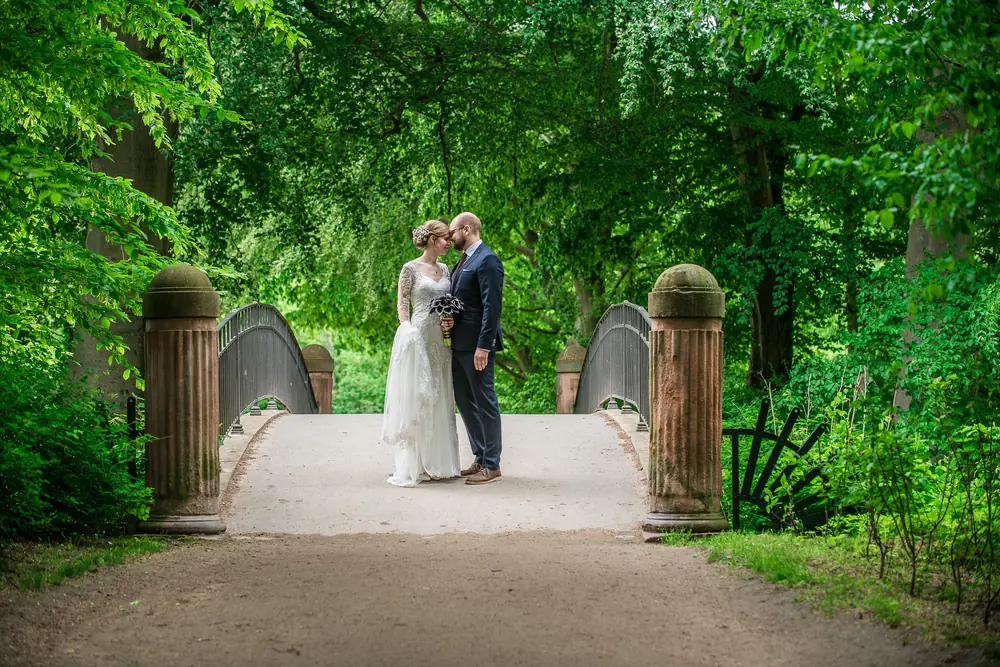 Wedding couple kissing on a bridge in a green park