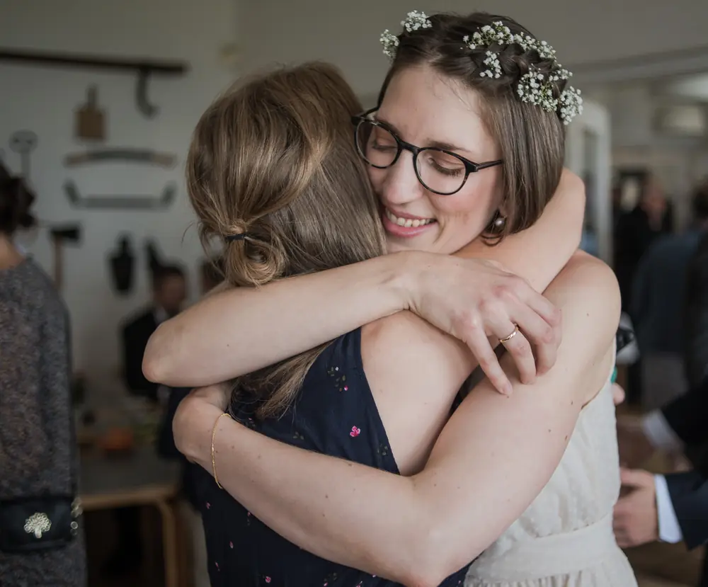 Bride with a flower crown hugging a wedding guest